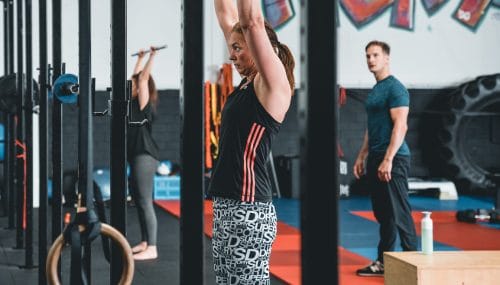 Two women holding weight bars over head on training at Bakker Sports Schagen